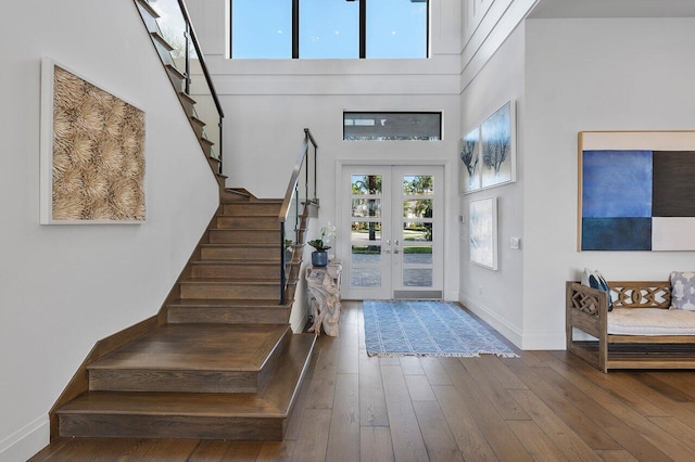 foyer entrance with dark hardwood / wood-style flooring, a towering ceiling, and french doors