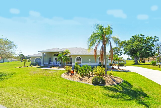 view of front of home with a front lawn, roof with shingles, and stucco siding