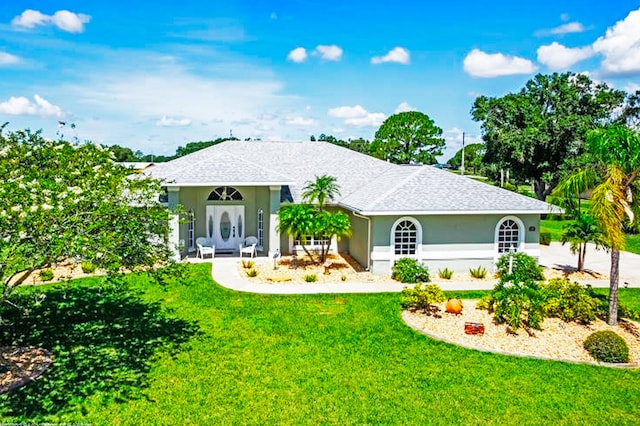 ranch-style house with a shingled roof, a front yard, and stucco siding