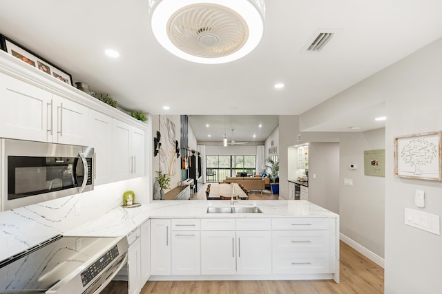 kitchen featuring white cabinetry, kitchen peninsula, light hardwood / wood-style flooring, sink, and appliances with stainless steel finishes