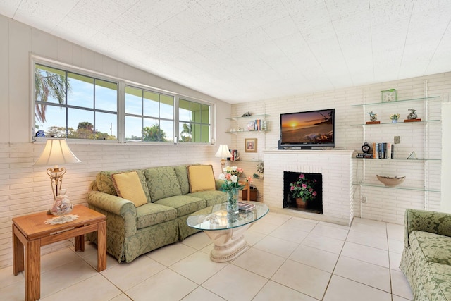 tiled living room featuring a brick fireplace and brick wall