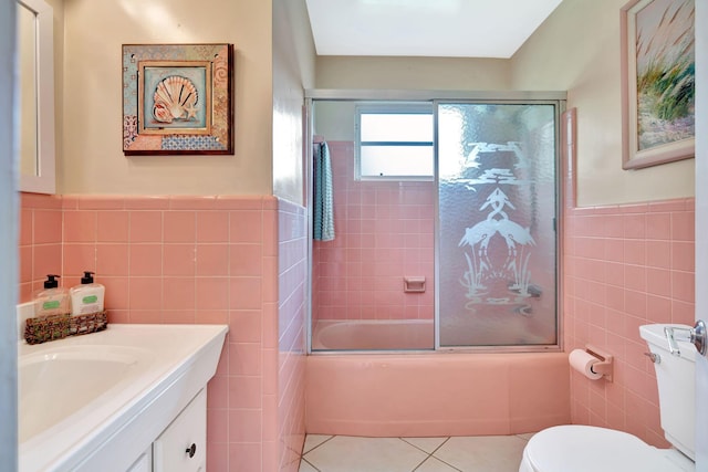 full bathroom featuring shower / bath combination with glass door, tile walls, vanity, tile patterned floors, and toilet