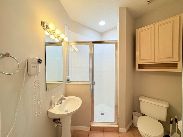 full bath with a stall shower, tile patterned flooring, toilet, and baseboards