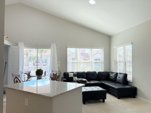 living room featuring high vaulted ceiling, light carpet, and baseboards