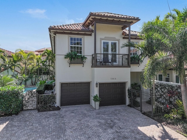 mediterranean / spanish-style home with a garage, a tile roof, fence, and stucco siding