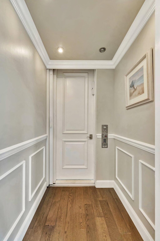 doorway to outside featuring dark wood-style floors, a decorative wall, a wainscoted wall, and crown molding