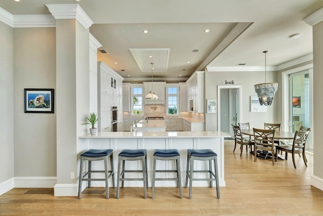 kitchen with a peninsula, ornamental molding, a breakfast bar, and light countertops