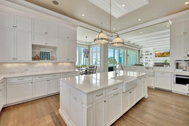 kitchen featuring stainless steel oven, a sink, and light wood finished floors