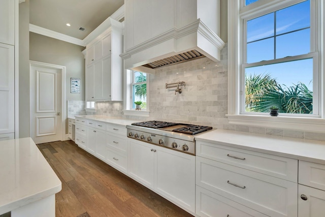 kitchen with stainless steel gas cooktop, premium range hood, white cabinetry, light countertops, and dark wood finished floors