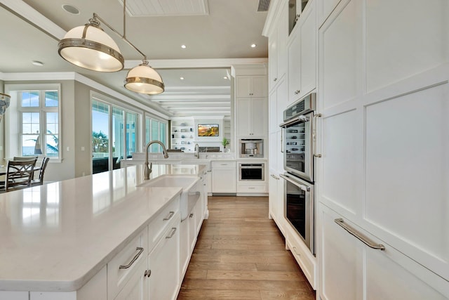 kitchen with a sink, light wood finished floors, white cabinets, and stainless steel double oven