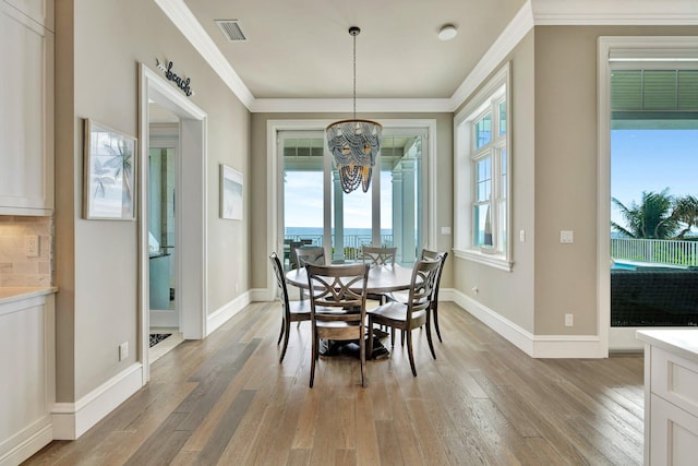 dining area featuring ornamental molding, light wood-style flooring, a chandelier, and visible vents