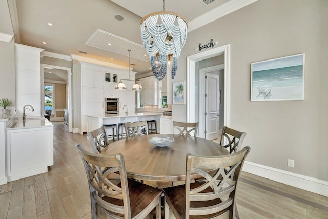 dining room with baseboards, an inviting chandelier, crown molding, light wood-type flooring, and recessed lighting