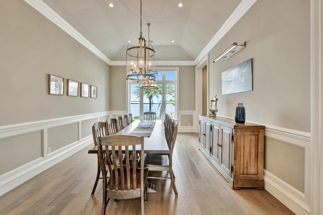 dining room featuring a chandelier, light wood-type flooring, vaulted ceiling, and crown molding