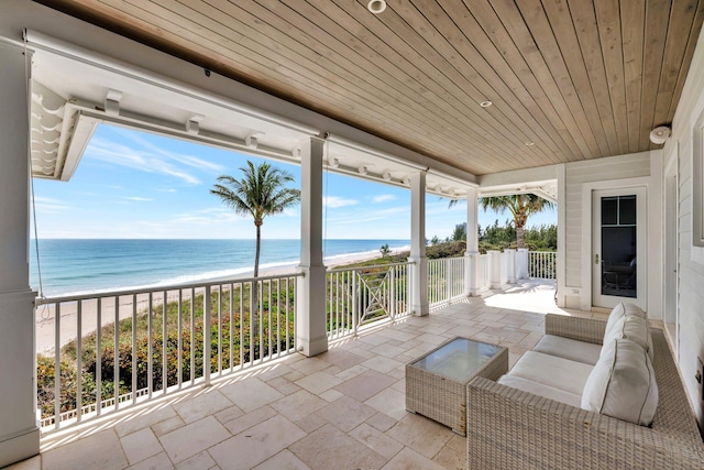 view of patio / terrace with an outdoor hangout area, a water view, and a view of the beach