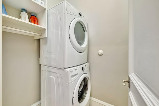 laundry area with laundry area, baseboards, and stacked washer and dryer