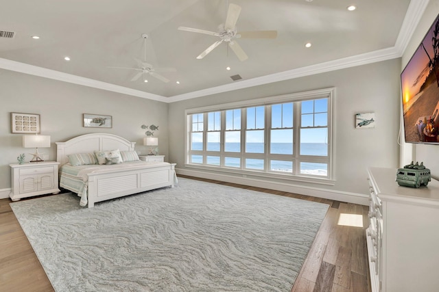 bedroom featuring ceiling fan, visible vents, baseboards, ornamental molding, and light wood-type flooring