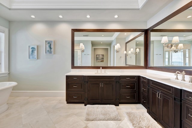 bathroom featuring recessed lighting, a freestanding tub, vanity, and baseboards