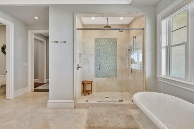 full bath featuring toilet, a stall shower, baseboards, and a freestanding tub