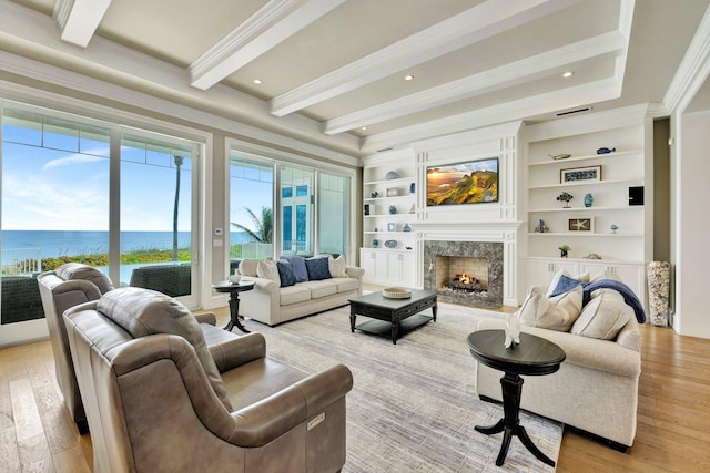 living area featuring recessed lighting, light wood-style floors, a high end fireplace, ornamental molding, and beamed ceiling