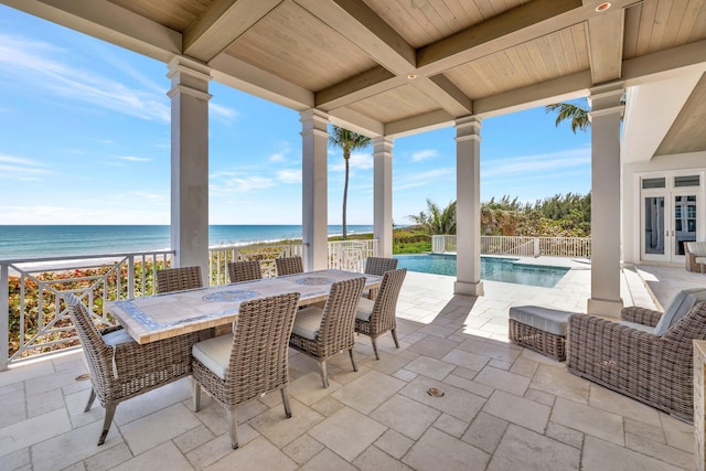 view of patio / terrace featuring a fenced in pool, outdoor dining area, french doors, a view of the beach, and a water view