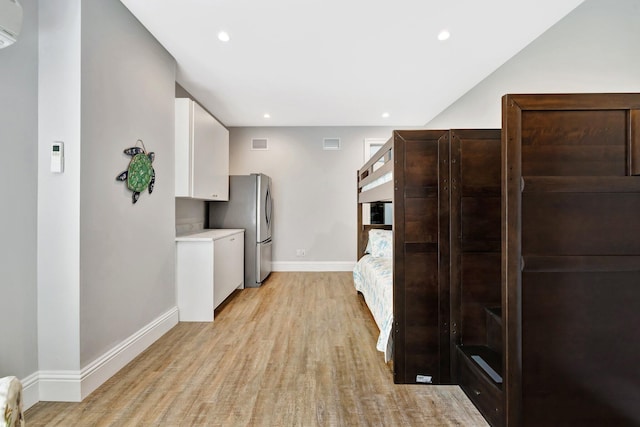 kitchen featuring baseboards, white cabinets, light countertops, freestanding refrigerator, and light wood finished floors