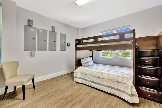 bedroom featuring electric panel, baseboards, and wood finished floors