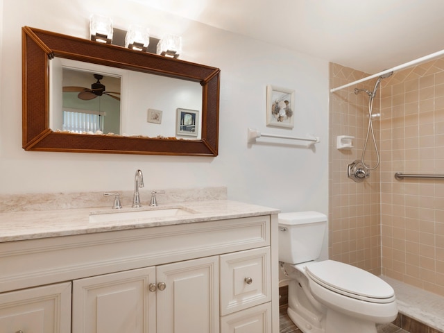 bathroom featuring ceiling fan, tiled shower, vanity, and toilet