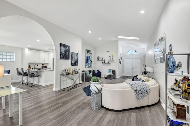 living room with light wood-type flooring, vaulted ceiling, and sink