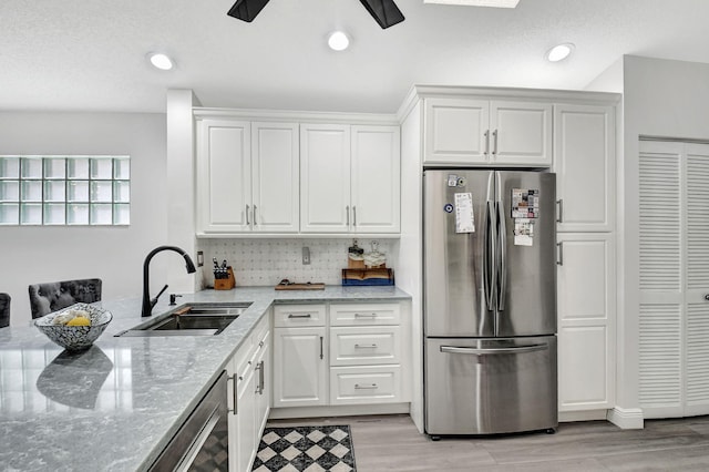 kitchen featuring stainless steel appliances, light stone counters, ceiling fan, sink, and white cabinetry