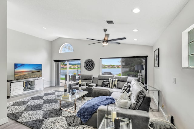 living room featuring ceiling fan, vaulted ceiling, a water view, and light hardwood / wood-style floors