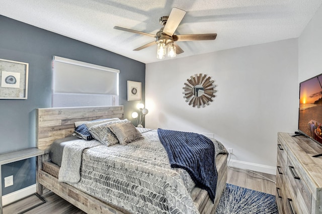 bedroom featuring ceiling fan, wood-type flooring, and a textured ceiling