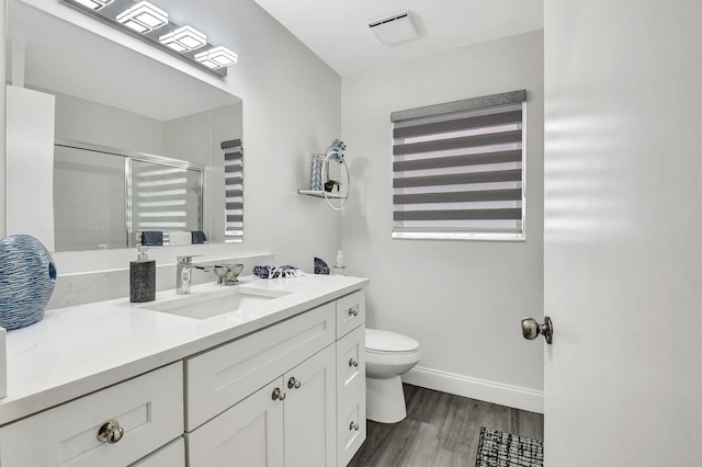 bathroom featuring toilet, vanity, an enclosed shower, and wood-type flooring