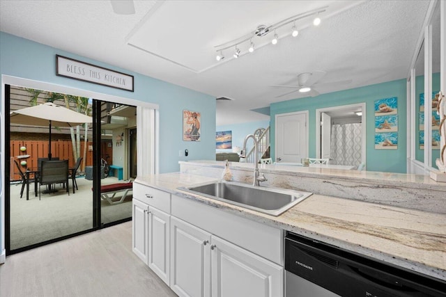 kitchen with sink, white cabinetry, dishwasher, ceiling fan, and light stone countertops