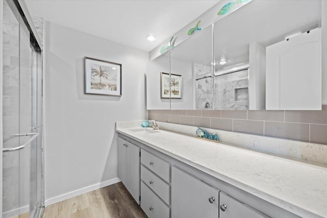 bathroom featuring hardwood / wood-style flooring, vanity, backsplash, and an enclosed shower