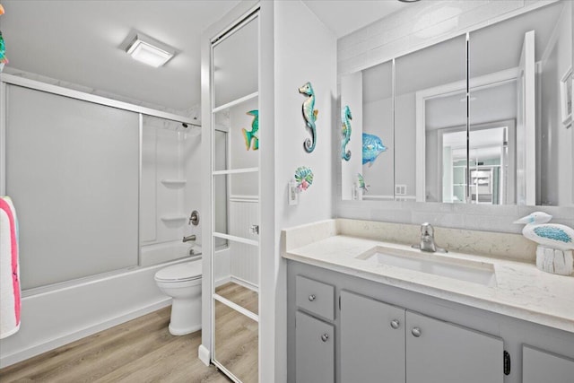 full bathroom with vanity, wood-type flooring, bath / shower combo with glass door, and toilet