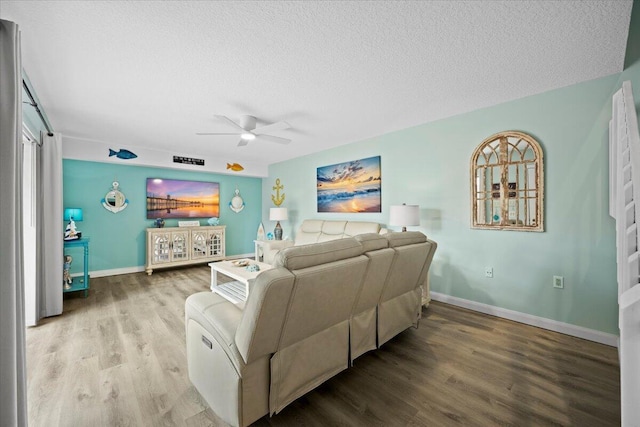 living room with hardwood / wood-style flooring, ceiling fan, and a textured ceiling