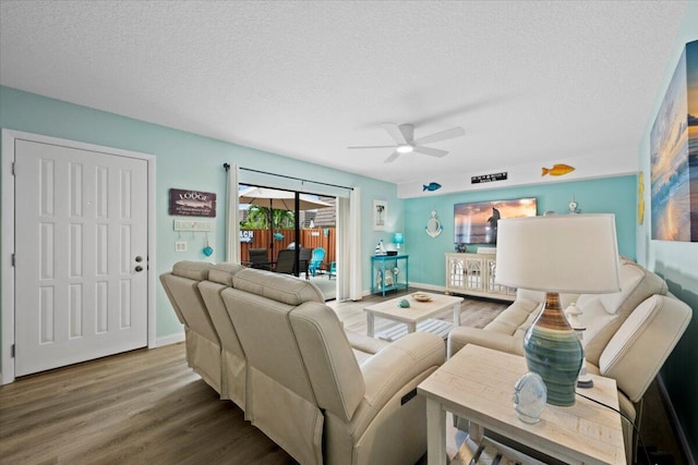 living room with ceiling fan, wood-type flooring, and a textured ceiling