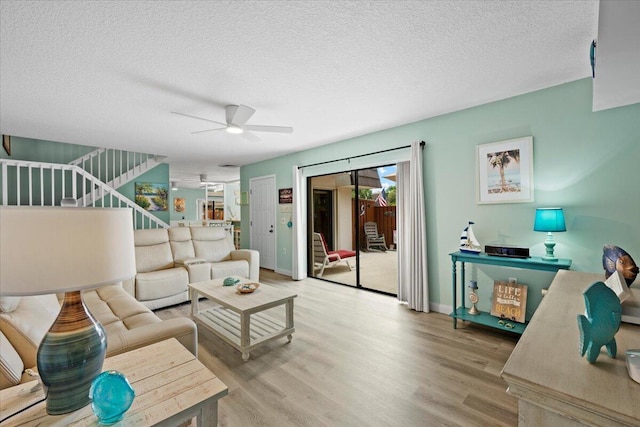 living room featuring ceiling fan, a textured ceiling, and light wood-type flooring