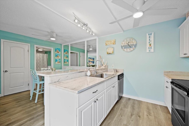 kitchen with appliances with stainless steel finishes, white cabinetry, sink, kitchen peninsula, and light wood-type flooring