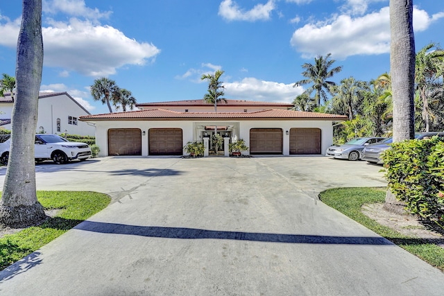 view of front of house featuring a garage, a tiled roof, and stucco siding