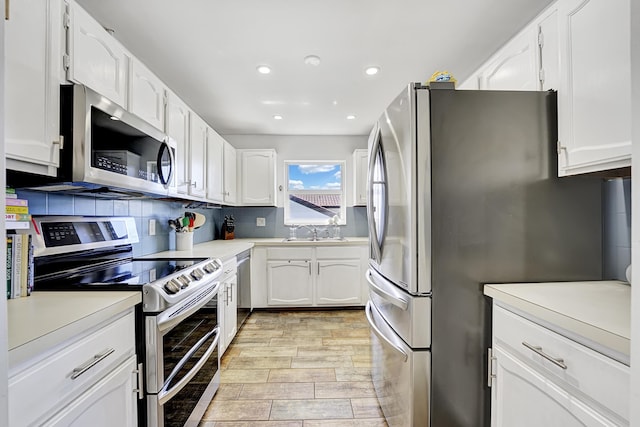 kitchen with sink, white cabinetry, tasteful backsplash, light wood-type flooring, and stainless steel appliances