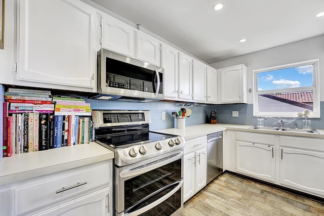 kitchen featuring sink, white cabinetry, light hardwood / wood-style flooring, appliances with stainless steel finishes, and decorative backsplash