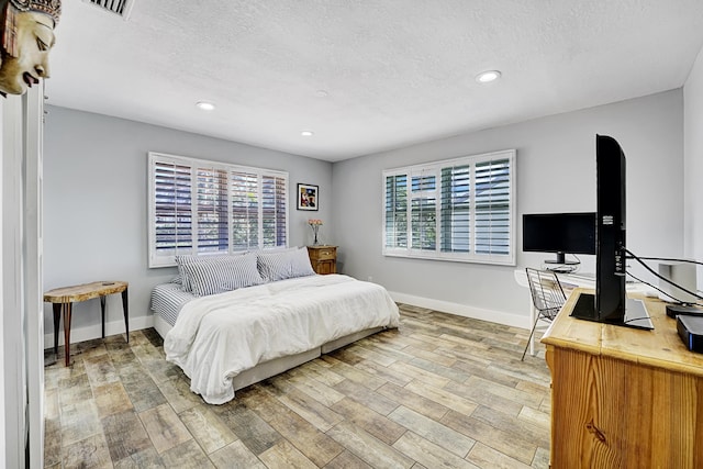 bedroom featuring multiple windows, hardwood / wood-style floors, and a textured ceiling