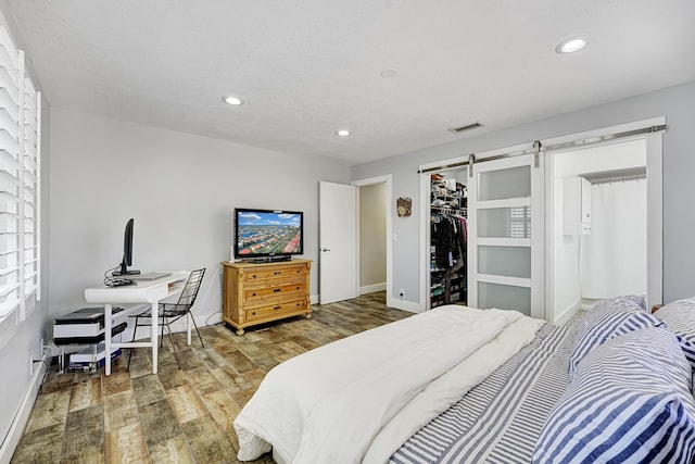 bedroom featuring a closet, a walk in closet, wood-type flooring, and a barn door