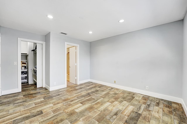 unfurnished bedroom featuring ensuite bath, light hardwood / wood-style floors, and a closet