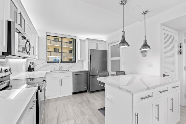 kitchen with light stone counters, stainless steel appliances, white cabinetry, pendant lighting, and a sink