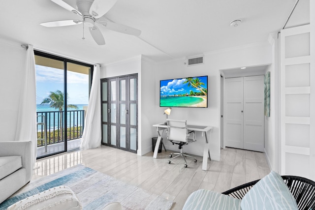 office space with baseboards, visible vents, light wood-style flooring, expansive windows, and crown molding