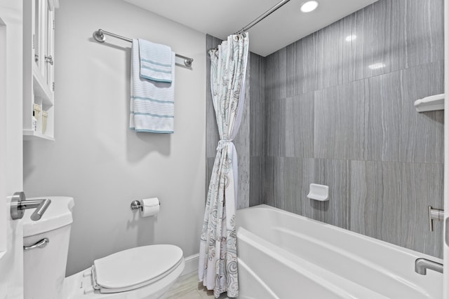 full bathroom with baseboards, shower / bath combo with shower curtain, and toilet