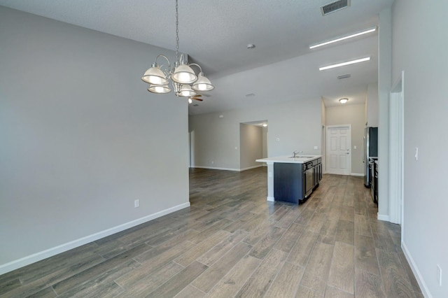 kitchen featuring pendant lighting, sink, an island with sink, dark hardwood / wood-style flooring, and a chandelier