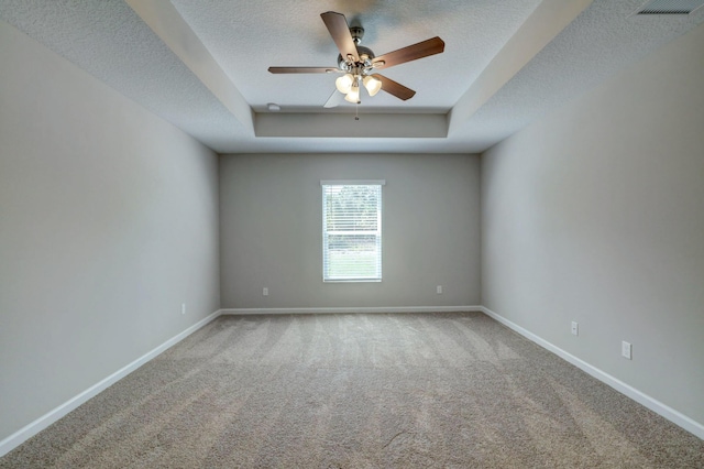 spare room with ceiling fan, a tray ceiling, carpet, and a textured ceiling